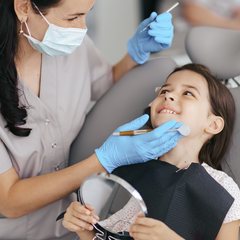 Dentist gently examining a smiling girl's teeth