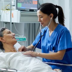 Nurse listening to a patient's heart in a hospital bed