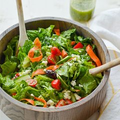 Wooden bowl of fresh green salad with tomato and carrot
